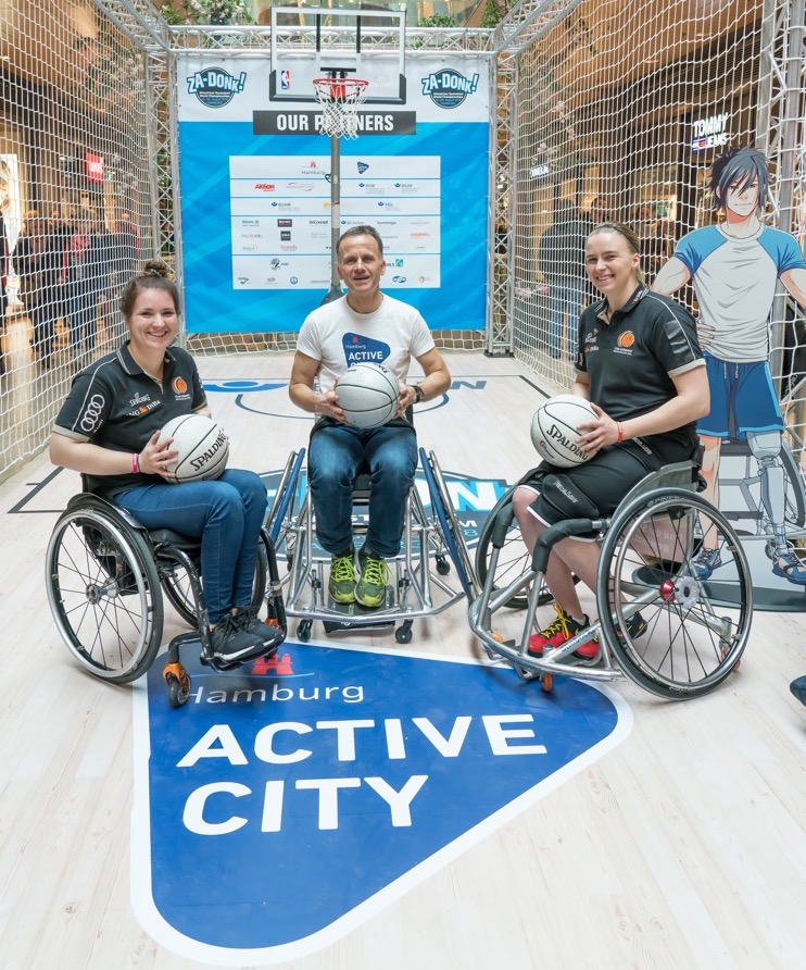 State Councillor Christoph Holstein tries wheelchair basketball with two national players.